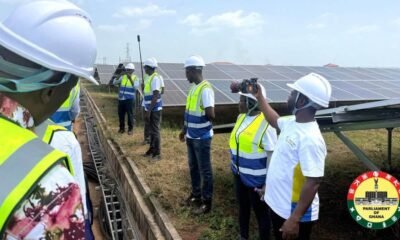 Visitors in safety vests inspect solar panels at the Galgu solar plant in Yendi
