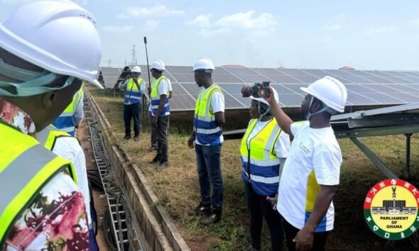 Visitors in safety vests inspect solar panels at the Galgu solar plant in Yendi