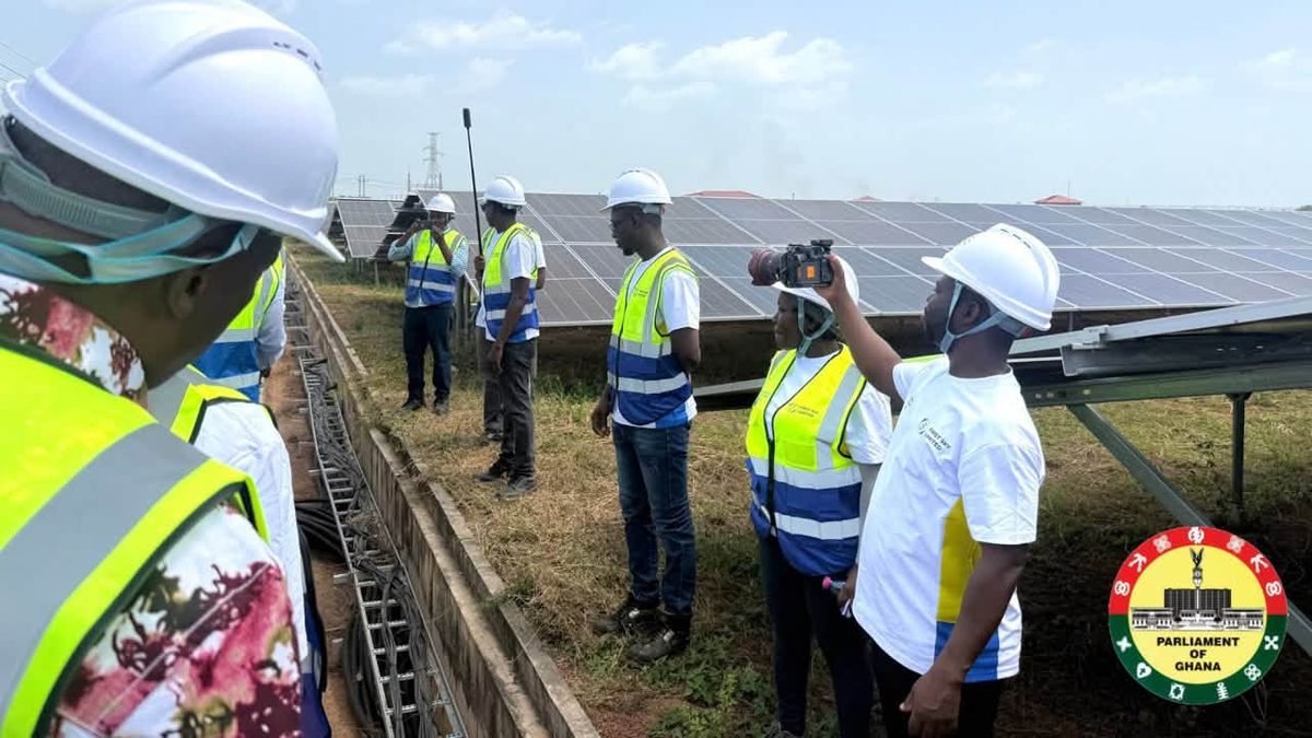 Visitors in safety vests inspect solar panels at the Galgu solar plant in Yendi